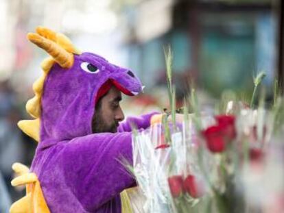 Un vendedor disfrazado de dragon prepara las rosas en una parada.