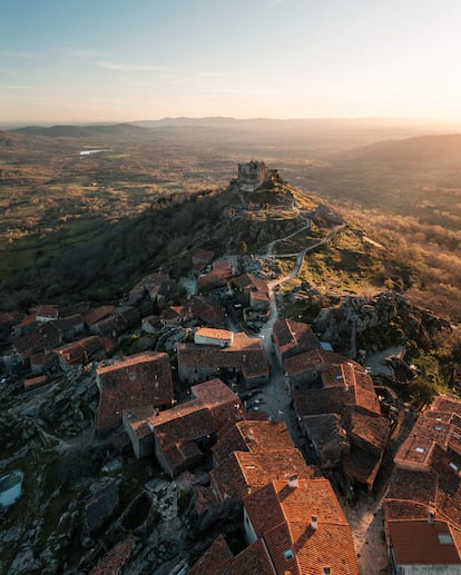 Trevejo (Cáceres). “Considerado como la esencia de la sierra de Gata, Trevejo es una sorpresa desde la propia carretera de acceso, rodeada de castaños que da entrada a este bello pueblo declarado de Interés Turístico por su cuidada arquitectura típica de la zona y bien conservada; una ubicación estratégica desde donde disfrutar de toda la comarca y las sierras de Garduño, Albilla, San Pedro y Cachaza, y las ruinas del castillo de Trevejo del siglo XV perteneciente a la Orden de San Juan de Jerusalén y de origen posiblemente musulmán”, resume la esencia de este lugar la Asociación de los Pueblos Más Bonitos de España. Considerada la esencia de la sierra de Gata, en el pasado esta pedanía (que no hay que confundir con San Martín de Trevejo) fue ocupada por musulmanes y cristianos por su privilegiada ubicación. La huella que dejaron aún es visible en su patrimonio histórico, entre el que destacan su arquitectura típica, el castillo (del siglo XV, y al que hay que subir al atardecer, cuando los rayos de sol doran los muros) y la iglesia de San Juan, con tumbas antropomórficas excavadas en roca granítica.