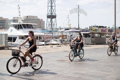 Varias turistas pasean en bicicleta por el puerto de Barcelona.