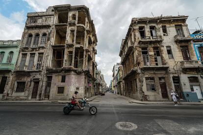 Una motocicleta pasa frente a dos edificios semidestruidos en La Habana, Cuba.