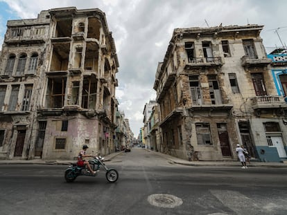 Una motocicleta pasa frente a dos edificios semidestruidos en La Habana, Cuba.