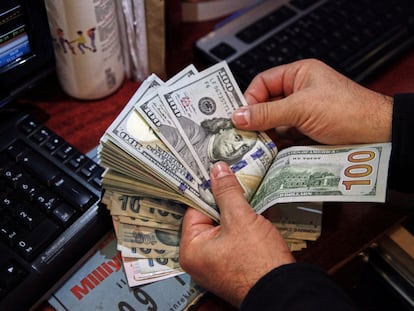 A money changer counts U.S. dollar banknotes at a currency exchange office in 2021.