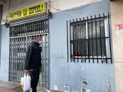 Un hombre pasa por delante de las velas que unos vecinos dejaron en la ventana del bar La Espuela.