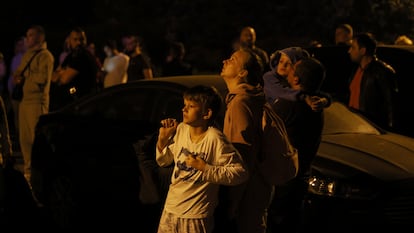 People look at a fire on the top of residential building following a drone attack, in Kyiv, Ukraine