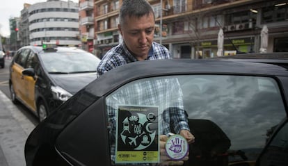 Un taxista col·loca al seu vehicle un adhesiu de la campanya violeta.