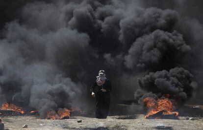 Una mujer camina entre el humo de unos neumáticos ardiendo durante la protesta en la frontera entre Gaza e Israel, el 14 de mayo de 2018.