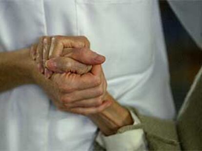 Una enfermera da la mano a una enferma de alzheimer en un centro de día.