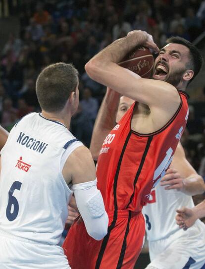 El ala-pívot español del Valencia Basket, Pierre Oriola (d), protege el balón ante el ala-pivot italiano del Real Madrid Andres Nocioni.