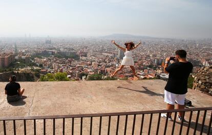 Una turista salta para una hacerse una fotografía con la ciudad de Barcelona de fondo.