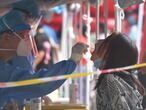 Health workers conduct a COVID-19 coronavirus swab test on a resident in Beijing on June 23, 2020. - Tens of thousands of people in the Chinese capital are being tested for the contagion while neighbourhoods have been locked down and schools closed as authorities seek to contain a cluster linked to the Xinfadi food market. (Photo by GREG BAKER / AFP)