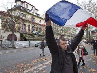 Um homem ergue a bandeira da França em frente ao Bataclan.