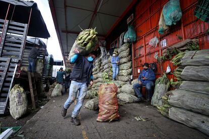 Um homem de máscara carrega um saco de milho em Corabastos, um dos maiores centros de distribuição de alimentos da América Latina, em Bogotá (Colômbia), na terça-feira da semana passada.