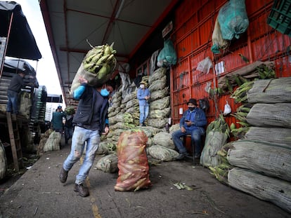 Um homem de máscara carrega um saco de milho em Corabastos, um dos maiores centros de distribuição de alimentos da América Latina, em Bogotá (Colômbia), na terça-feira da semana passada.