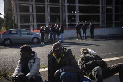 Varios migrantes sentados frente a la fbrica tras ser desalojados por la polica y los carabineros.