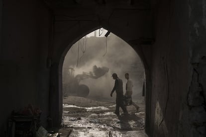 Trabajadores cargan un generador mientras las excavadoras realizan tareas de limpieza entre los escombros en la zona comercial de la Ciudad Vieja de Mosul. A lo largo de las carreteras destruidas del vecindario, un puñado de personas está empezando a reconstruir, pero la tarea que se avecina llevará años y miles de millones de dólares.