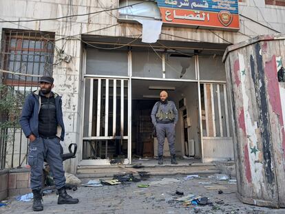 Dos policías del Gobierno rebelde en Idlib custodian una comisaría atacada en la víspera, este lunes en Damasco. En el cartel ha sido arrancada la imagen de Bashar El Asad