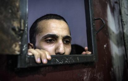 Un preso asoma su rostro por una ventanilla de la celda.