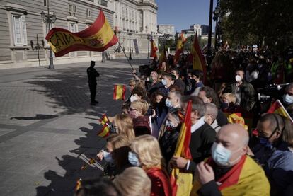 Un grupo de manifestantes, frente al Palacio Real de Madrid, protesta contra el Gobierno mientras se celebran los actos de la Fiesta Nacional.