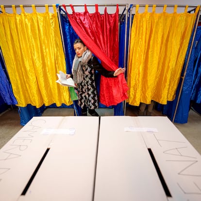 A woman exits a voting cabin with the colours of the Romanian flag as curtains before casting her vote in the country's parliamentary elections, in Bucharest, Romania, Sunday, Dec. 1, 2024. (AP Photo/Andreea Alexandru)