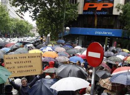 Uno de los asistentes a la concentración  frente a la sede nacional del PP muestra una pancarta en la que pide que el líder del partido sea elegido directamente por los militantes.