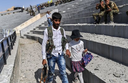 Un combatiente sirio camina con su hija en el estadio de Raqa este viernes durante las celebraciones de la proclamación oficial de liberación de la ciudad.