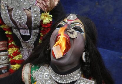 Un hombre indio vestido de la diosa hindú Kali realiza una actuación con fuego durante una procesión para conmemorar el festival Mahashivratri en Allahabad (India).