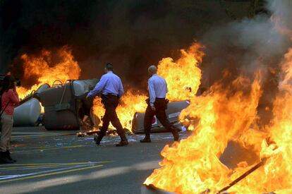 Una pareja de los Mossos d'Esquadra, camina por entre unos contenedores incendiados en la calle Balmes de Barcelona.