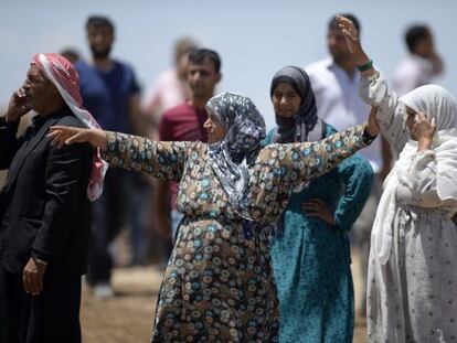 Diverses kurdes esperen els seus parents fugits de Kobane a la frontera.