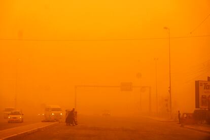 Los peatones cruzan una carretera durante la grave tormenta de arena en la capital de Irak, Bagdad, el día 16 de mayo. 