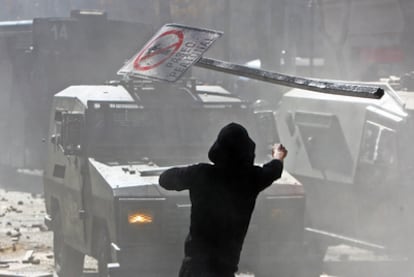 Un estudiante lanza una señal de tráfico contra la policía durante las protestas en Santiago.