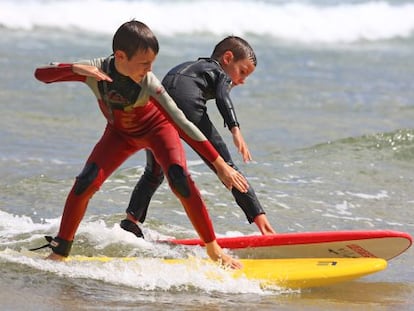 Dos ni&ntilde;os surfeando durante un campamento en la playa de Somo (Cantabria).