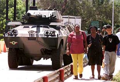 Tres venezolanos pasan junto a un carro de combate del Ejército, ayer en Caracas.