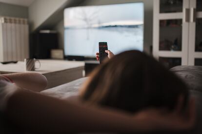 Una mujer se relaja en un sofá viendo la televisión.