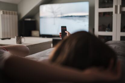 Una mujer se relaja en un sofá viendo la televisión.