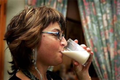 Una mujer toma un vaso de leche.