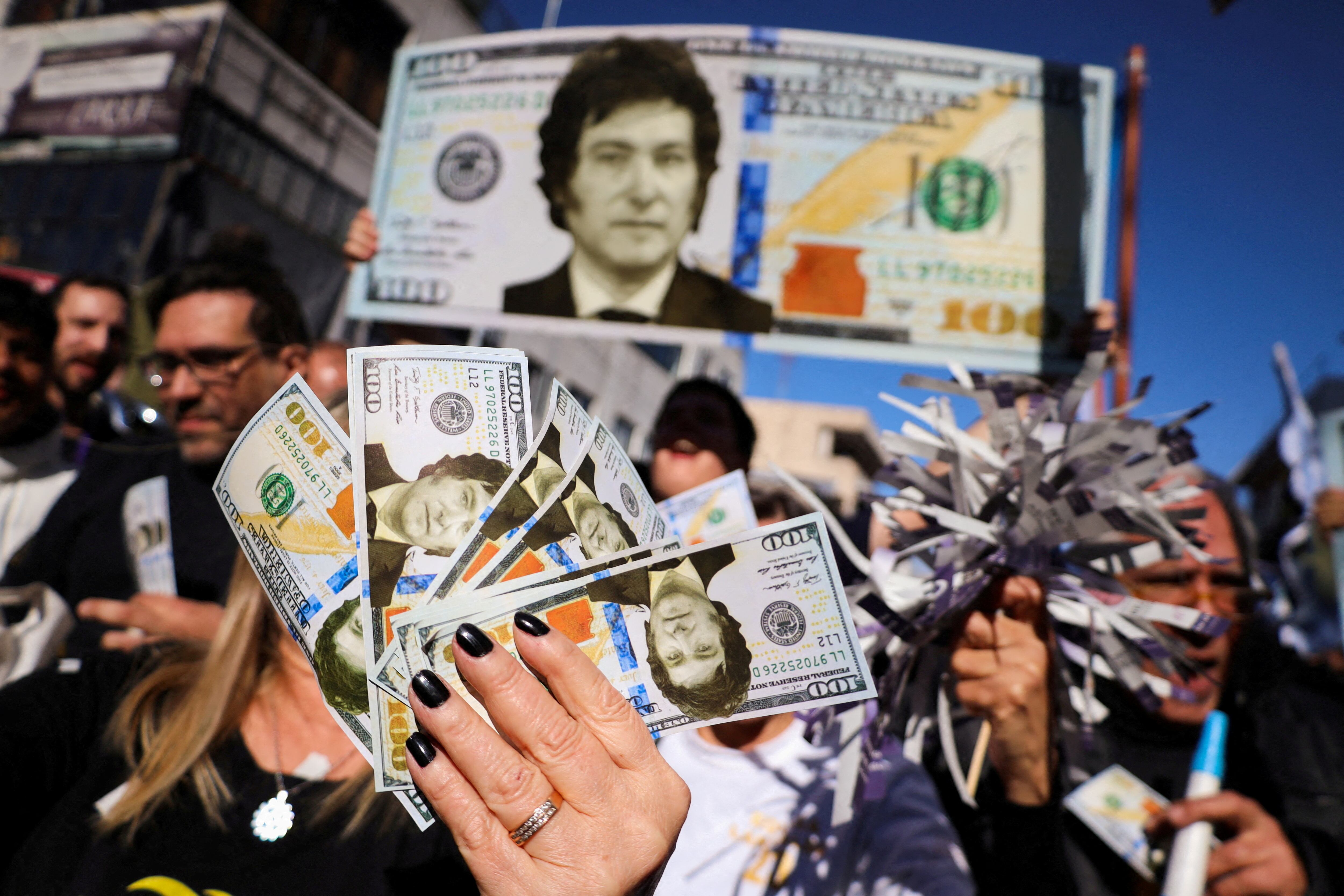 Simpatizantes de Javier Milei, candidato ultra a la presidencia argentina, agitan reproducciones de dólares con su cara en un mitin celebrado en Buenos Aires.