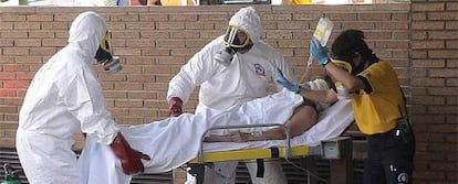 Sanitarios del Samur con trajes de protección contra el riesgo químico atienden ayer a la mujer.