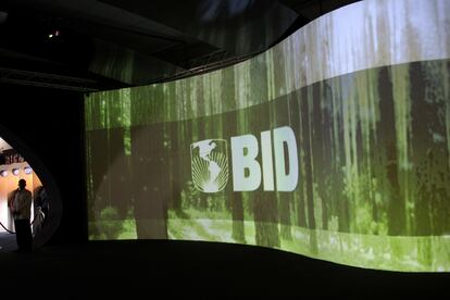 Um homem em frente a um logo do BID, em um centro de convenções no Panamá.