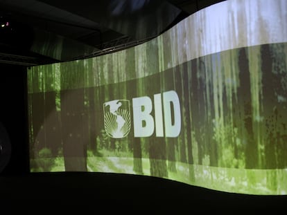 Um homem em frente a um logo do BID, em um centro de convenções no Panamá.