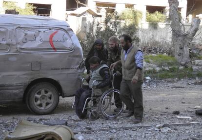 Civilians push a man on a wheelchair towards a meeting point to be evacuated from a besieged area of Homs February 9, 2014. Six hundred people left the besieged ruins of rebel-held central Homs on Sunday, escaping more than a year of hunger and deprivation caused by one of the most protracted blockades of Syria's devastating conflict. The evacuees, mainly women, children and old men, were brought out by the United Nations and Syrian Red Crescent on the third day of an operation during which the aid convoys came under fire and were briefly trapped themselves in the city. Picture taken February 9, 2014.  REUTERS/Thaer Al Khalidiya (SYRIA - Tags: POLITICS CIVIL UNREST HEALTH CONFLICT)