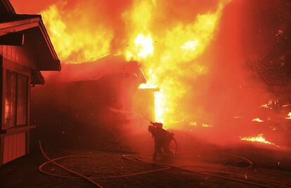 Un bombero intenta proteger una casa del fuego en Coffey Park, California.
