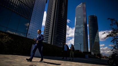 Un hombre con traje pasea por la zona la de las cuatro torres del Paseo de la Castellana, en Madrid.