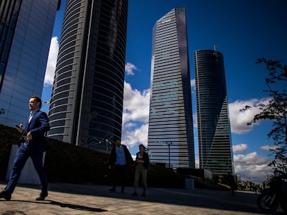 Un hombre con traje pasea por la zona la de las cuatro torres del Paseo de la Castellana, en Madrid.