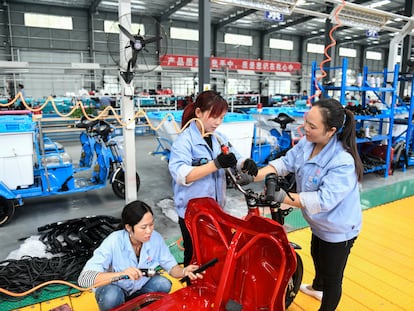 Empleados en una cadena de producción de motocicletas eléctricas en Qinglong, en la provincia china de Guizhou.