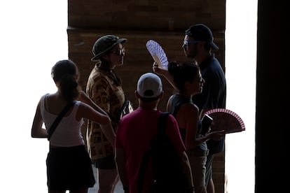 Unos turistas intentan refugiarse del calor este viernes en la Plaza de España de Sevilla. 