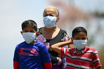 Una mujer y dos niños con mascarilla en Jiquilisco, municipio de El Salvador.