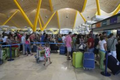 Decenas de turistas hacen cola para facturar sus maletas en el aeropuerto de Barajas en Madrid. EFE/Archivo