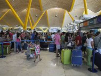 Decenas de turistas hacen cola para facturar sus maletas en el aeropuerto de Barajas en Madrid. EFE/Archivo