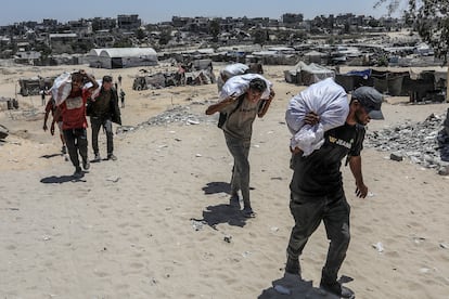 A group of Palestinians carry sacks of flour after a humanitarian aid distribution in Rafah, southern Gaza Strip, on July 31, 2025.