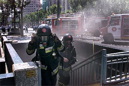 Dos bomberos salen del aparcamiento del paseo de Gràcia de Barcelona tras participar en la extinción del incendio que se declaró ayer.